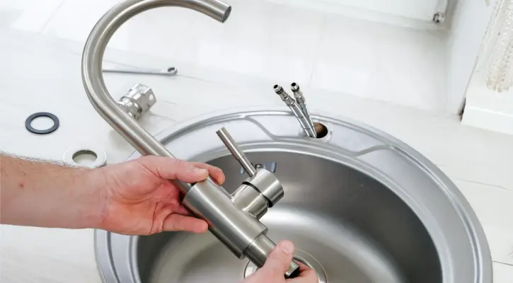 Plumber installing a new bathroom faucet during professional fixture installation in McLean County