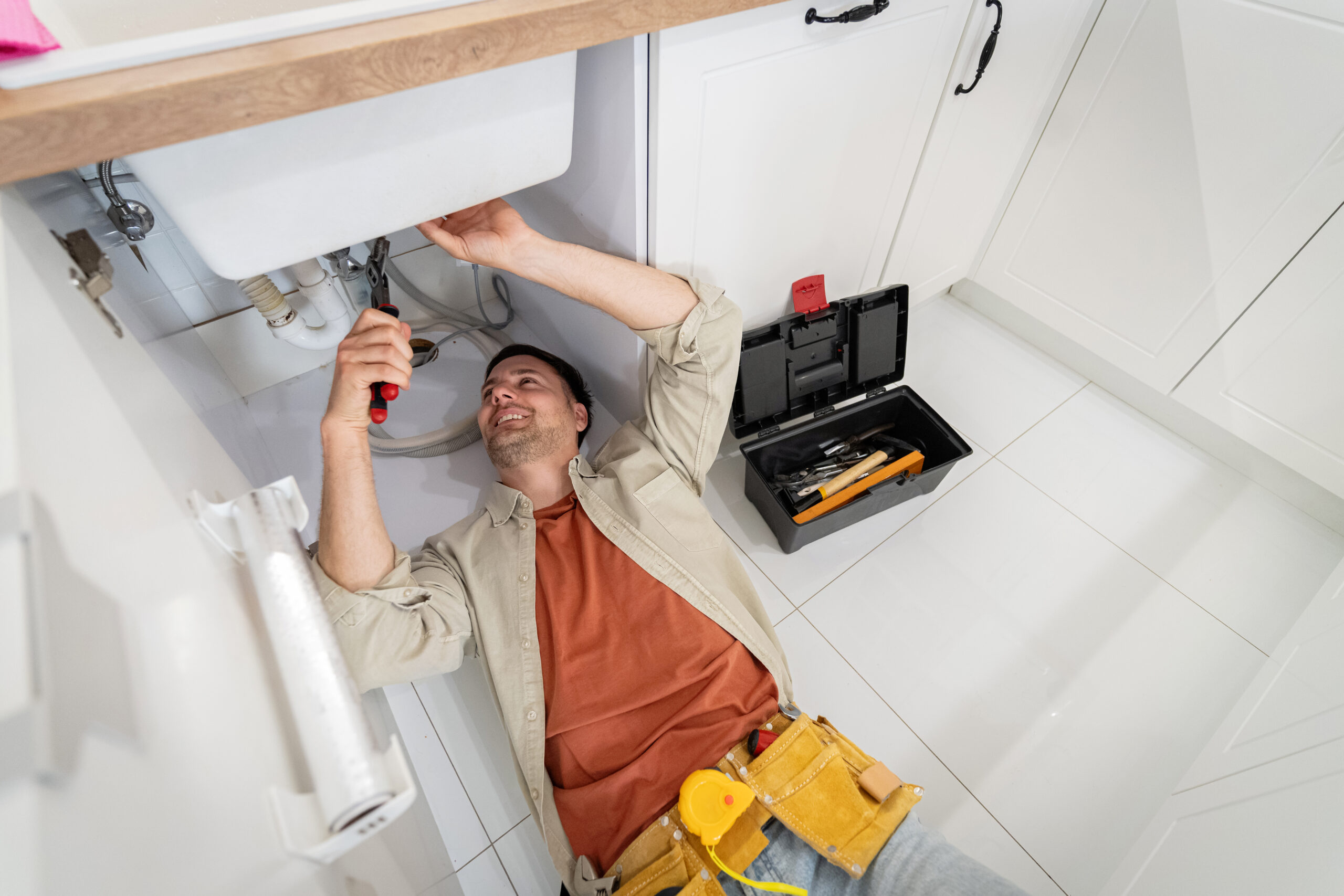 Plumber repairing sink under kitchen cabinet, Clogged Drain Repair Bloomington IL